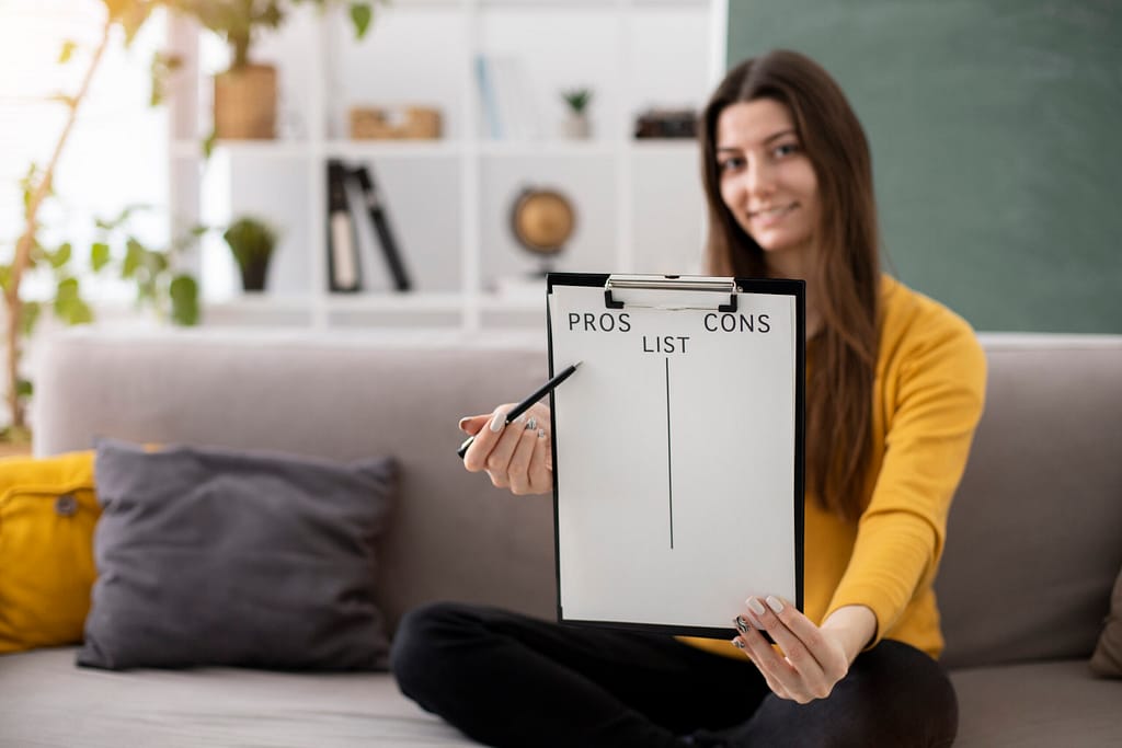 A picture of a young woman displaying a clipboard with a list for pros and cons.