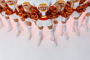 pexels-mart-production-7894476 - IA Solutions A group of female cheerleaders holding pom-poms.