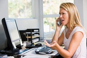 angry woman on phone facing computer screen showing why agents need to personalize the customer journey.