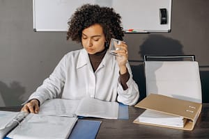 Woman holding a glass while reading an RFP.