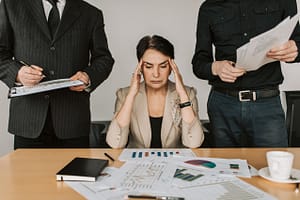 Stressed elderly woman holding her head while sitting at her desk.